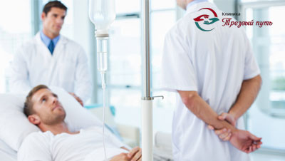 Пациент лежит под капельницей, рядом два врача стоят